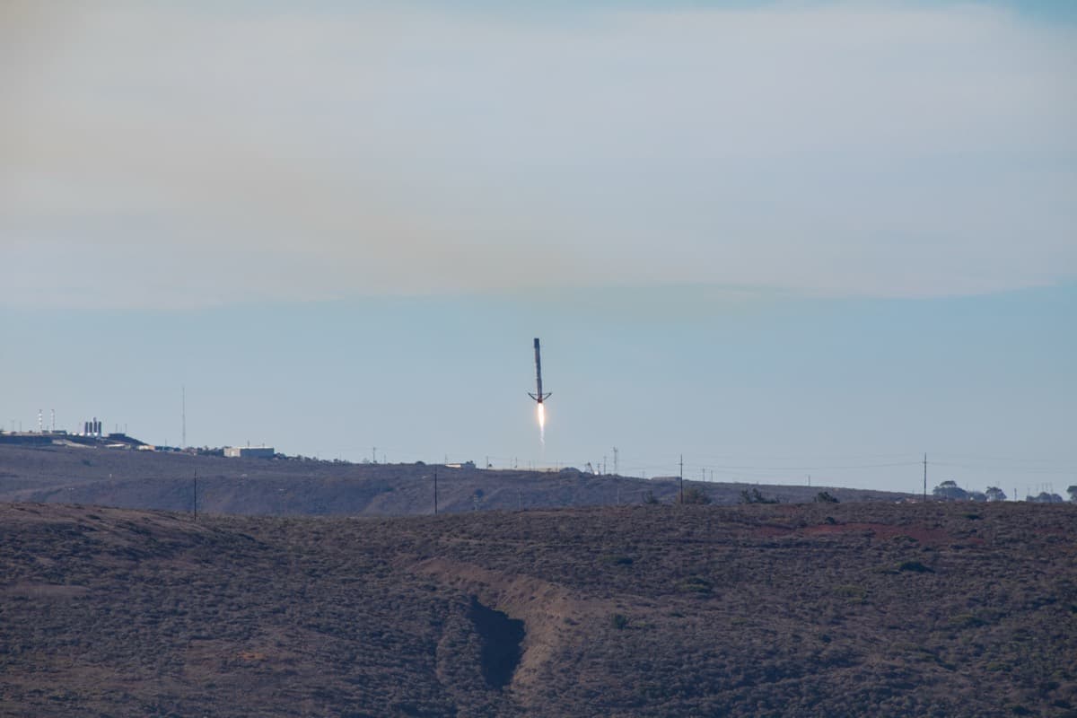 A SpaceX Falcon 9 first-stage booster descending to land upright, the reusable-rocket capability that underpins the company's launch economics