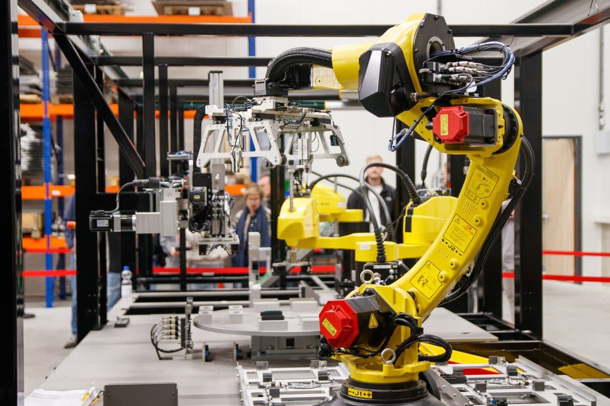 An industrial robotic arm performing automated assembly work, illustrating the embodied AI systems built on open source robotics stacks