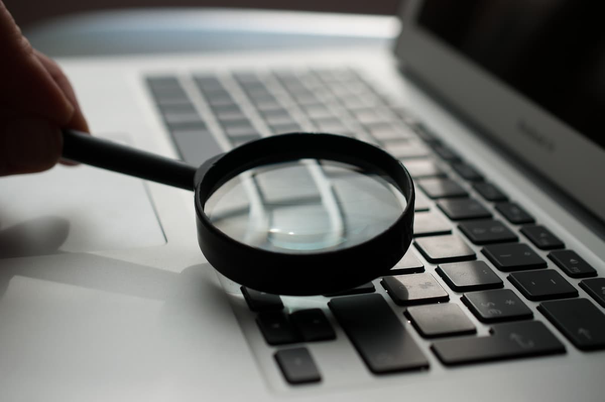 A magnifying glass rests beside a laptop, representing a website SEO audit