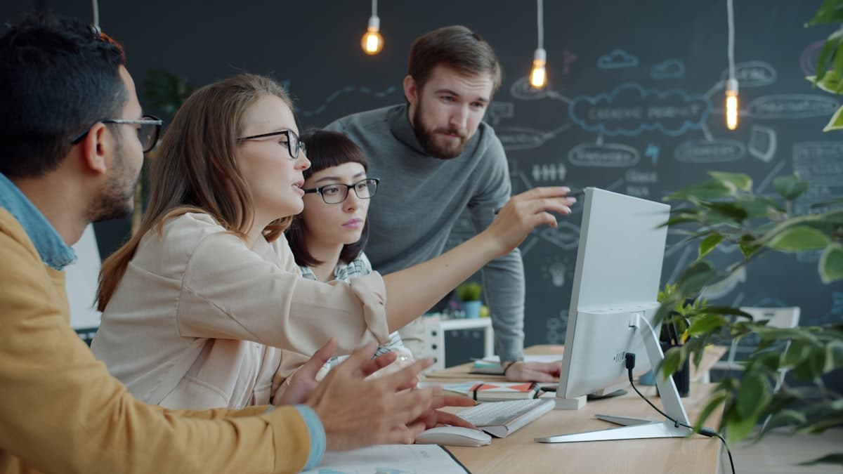 A marketing team collaborates around a laptop screen reviewing website performance data