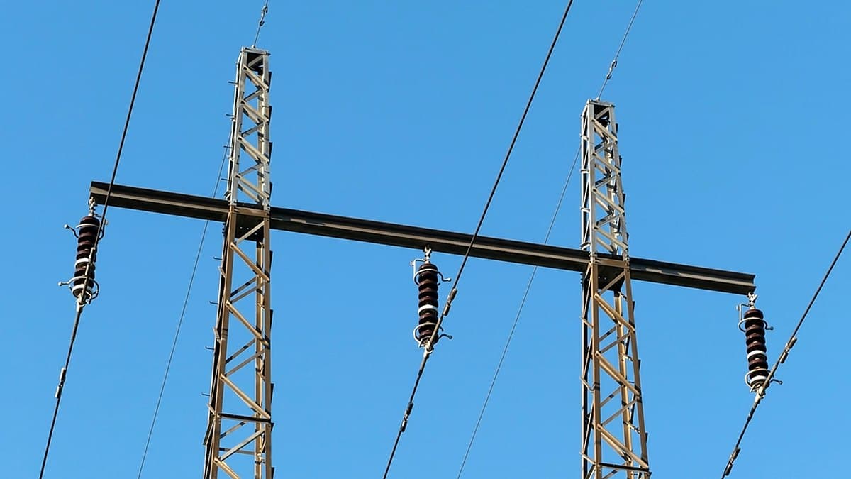 Two high-voltage transmission pylons and their insulators against a clear sky, the grid capacity at the centre of the AI power debate