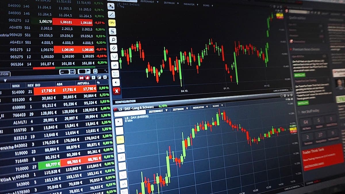 Financial charts and market data displayed on trading screens, the kind of forecast evidence against which Musk's 20 to 30 percent GDP claim can be measured